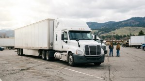 semi-truck with trailer parked in lot with two people standing nearby