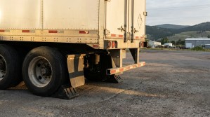 rear undercarriage of parked semi-truck trailer with dual tires and wheel chocks