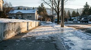 icy residential sidewalk with snow patches and concrete retaining wall in winter